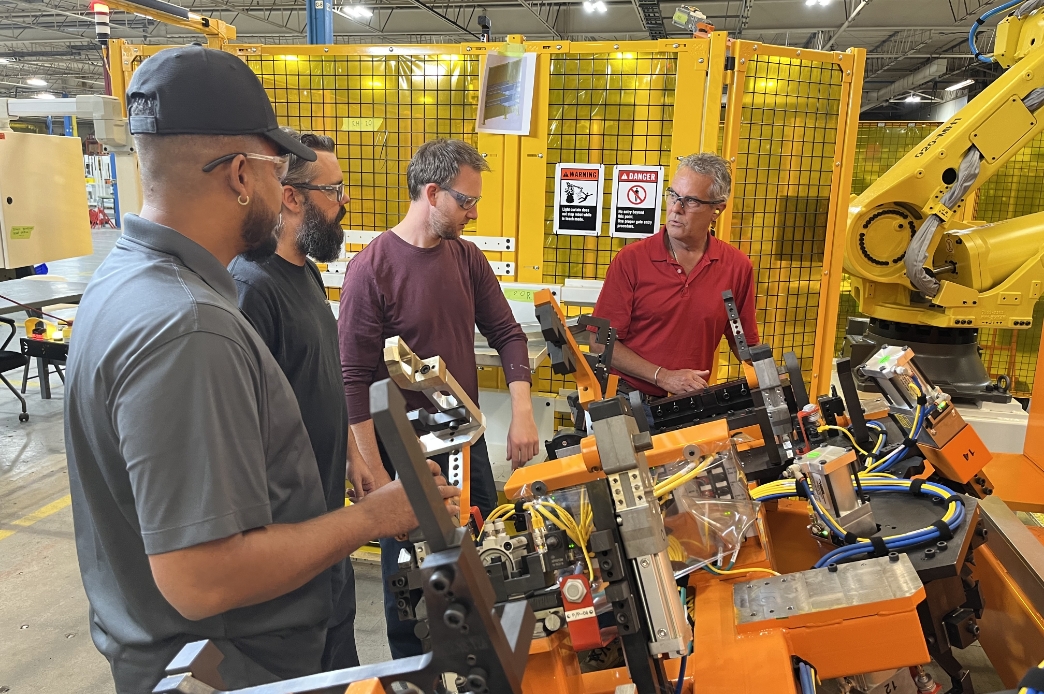 prodomax team standing over an assembly system and talking