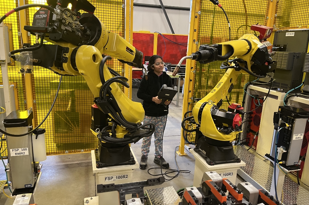 Student standing in a cell operating machinery