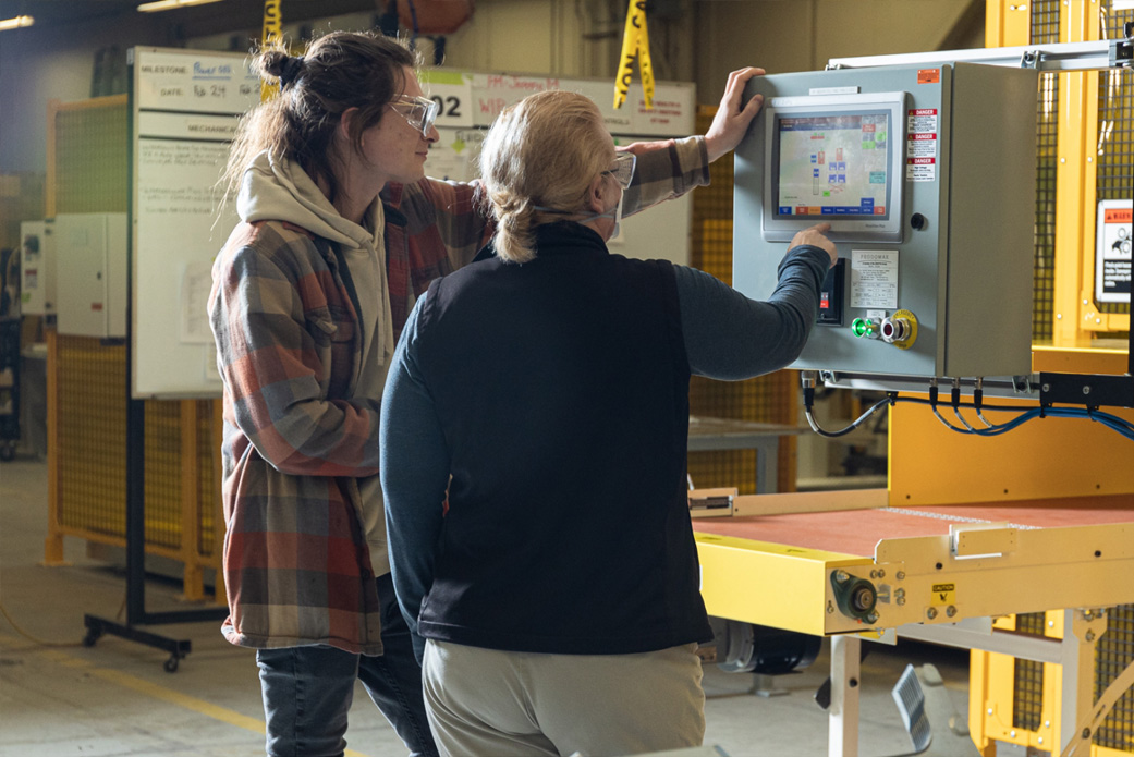 two female prodomax team members using a control panel in a cell